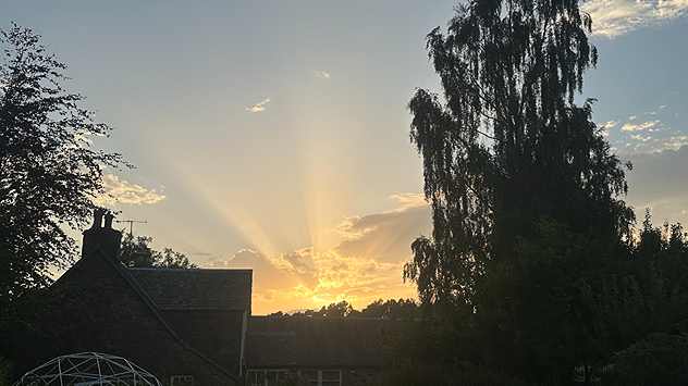 Crepuscular rays shine from cloud cover at sunset.