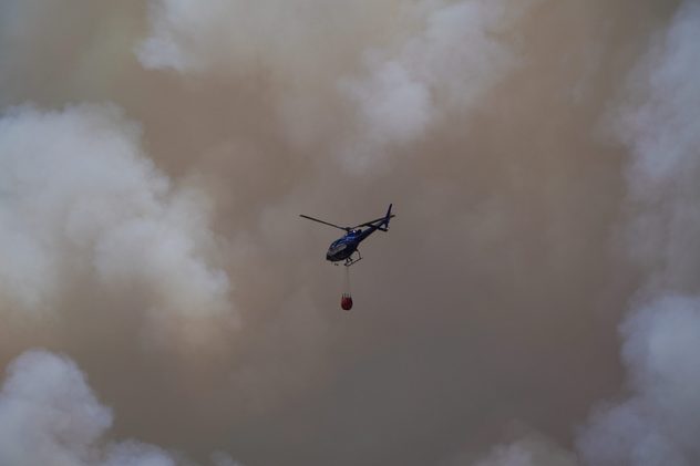 Helicópteros en acción para contener los incendios que asolan las proximidades de la ciudad metropolitana de Santiago.