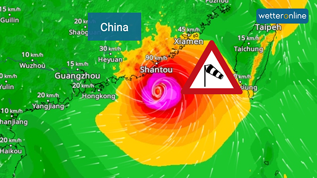 Wetterkarte der südchinesischen Küste und Taiwans mit einem kräftigen tropischen Wirbelsturm. Das Auge des Sturms liegt nahe der Küstenstadt Shantou in der chinesischen Provinz Guangdong. Um den Kern zeigen intensive Rot-, Pink- und Violetttöne Orkanböen, während ein großes orangefarbenes Windfeld bis zur Westküste Taiwans reicht. Ein eingeblendetes Windsack-Warnschild weist auf gefährliche Sturmwinde hin. Städte wie Hongkong, Guangzhou, Xiamen, Taipeh und Taichung sind eingezeichnet, ebenso Windgeschwindigkeiten und weiße Strömungslinien, die die zyklonale Luftzirkulation veranschaulichen.