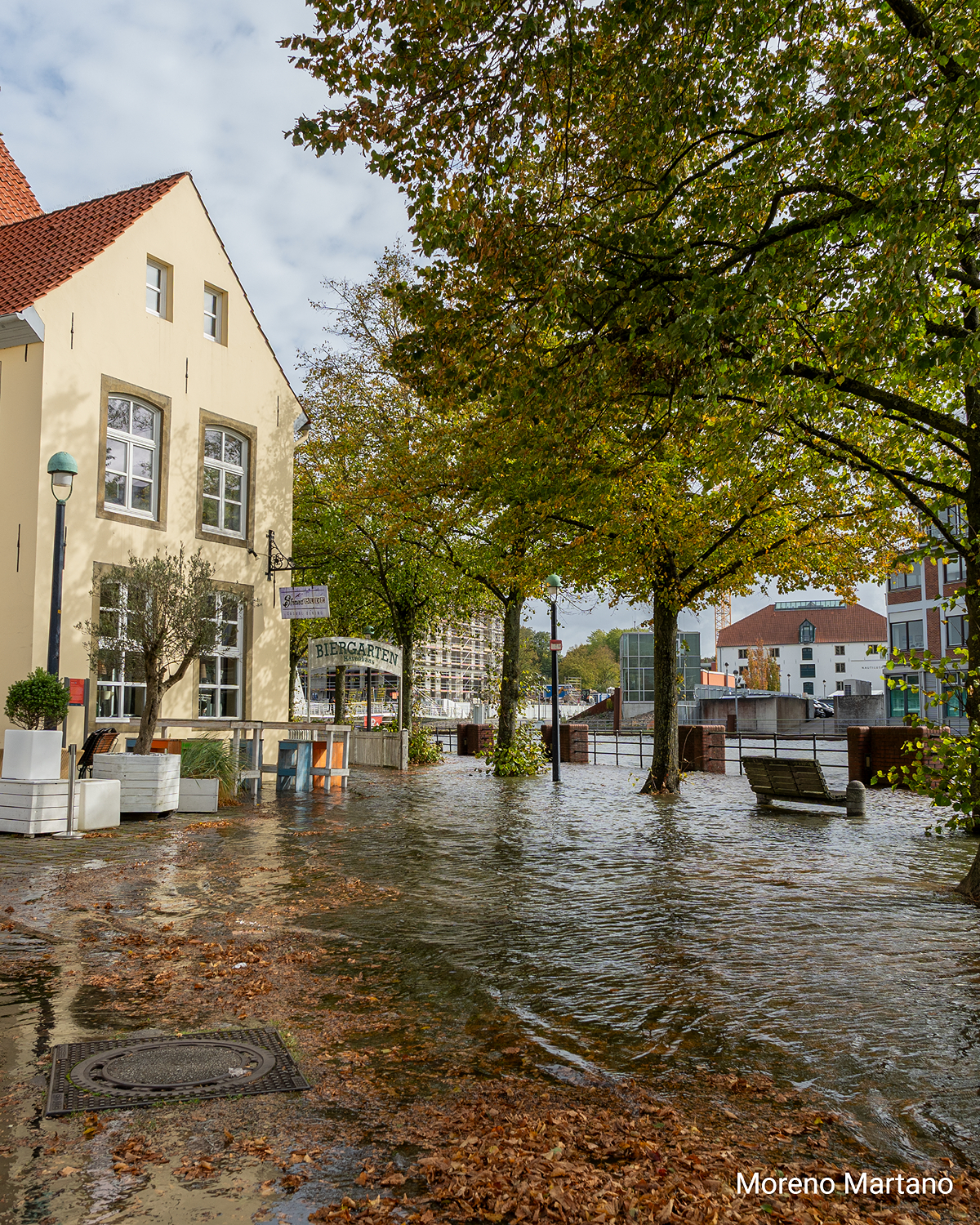 Überflutete Straßen und Wege am Weserufer in Bremen infolge einer Sturmflut, Wasser reicht bis an Gebäude und Bäume.