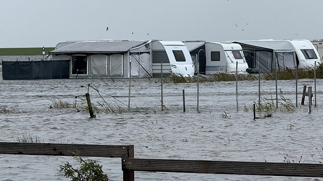 Überfluteter Campingplatz mit Wohnwagen und Vorzelten, Wasser steht hoch, grauer Himmel und Sturm an der Nordsee. (c) NonstopNews