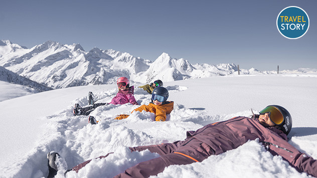 Kinder liegen auf dem Rücken im Schnee und Genießen die Sonne.