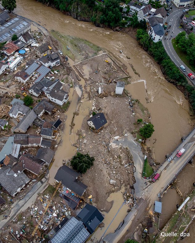 Luftaufnahme eines durch die Flut verwüsteten Ortes mit zerstörten Straßen und Gebäuden.