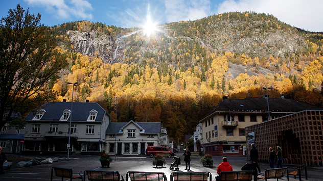A large mirror on the side of a mountain reflected sunlight towards a town in darkness due to its location within a valley.
