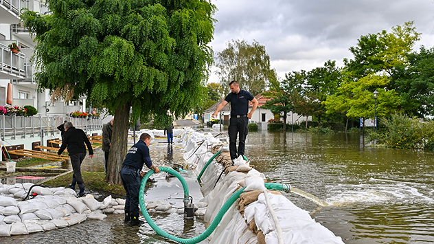 Einsatzkräfte der Feuerwehr und Anwohner kämpfen mit vereinten Kräften gegen das Hochwasser.