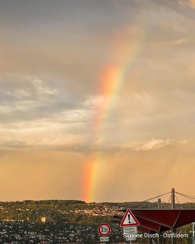 Kräftiger Regenbogen über Ostfildern vor einem gelblich-grauen Himmel mit Regenwolken.