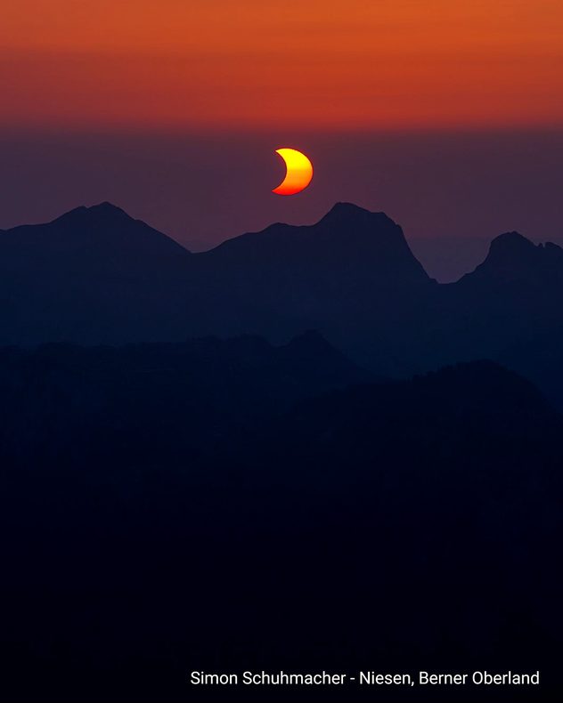 Leuchtende Sonnensichel einer partiellen Sonnenfinsternis über dunklen Berggipfeln im Berner Oberland.