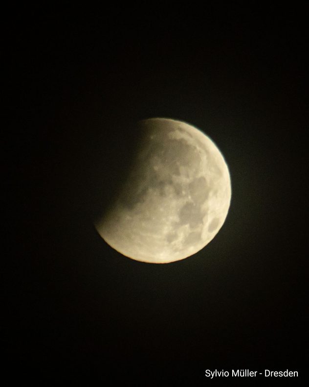 Teilweise verfinsterter Mond vor schwarzem Nachthimmel während einer partiellen Mondfinsternis.