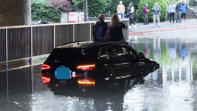 Menschen auf Autos, von Wassermassen eingeschlossen.