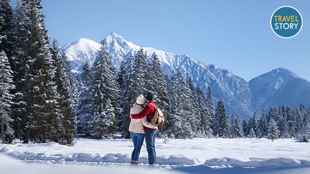 Ein Paar, das sich umarmt und auf verschneite Berggipfel blickt. (c) TVB Seefeld