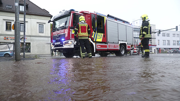 Ein Feuerwehrfahrzeug steht auf einer überfluteten Straße.